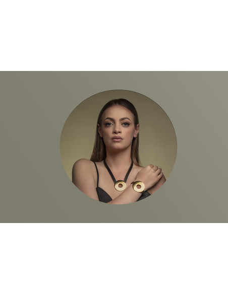 Black leather necklace with large shiny gold-plated stainless steel circular pendant.